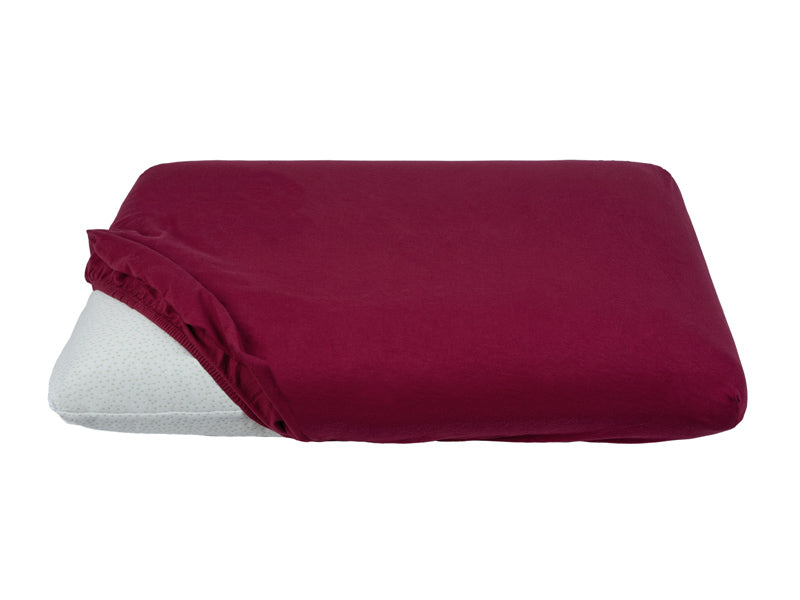Teilweise bezogenes Kopfkissen mit einem weinroten Kopfkissen-Spannbezug auf einem weissen Hintergrund.