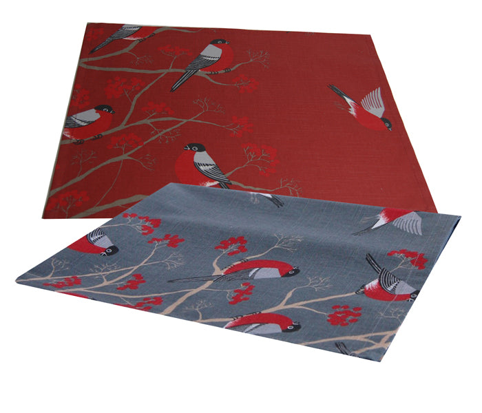 Ein rotes und ein graues rechteckiges Platzset auf einem weissen Hintergrund. Die Platzsets sind mit rot-grau-schwarzen Voegeln, die auf Zweigen mit roten Beeren sitzen, bedruckt.