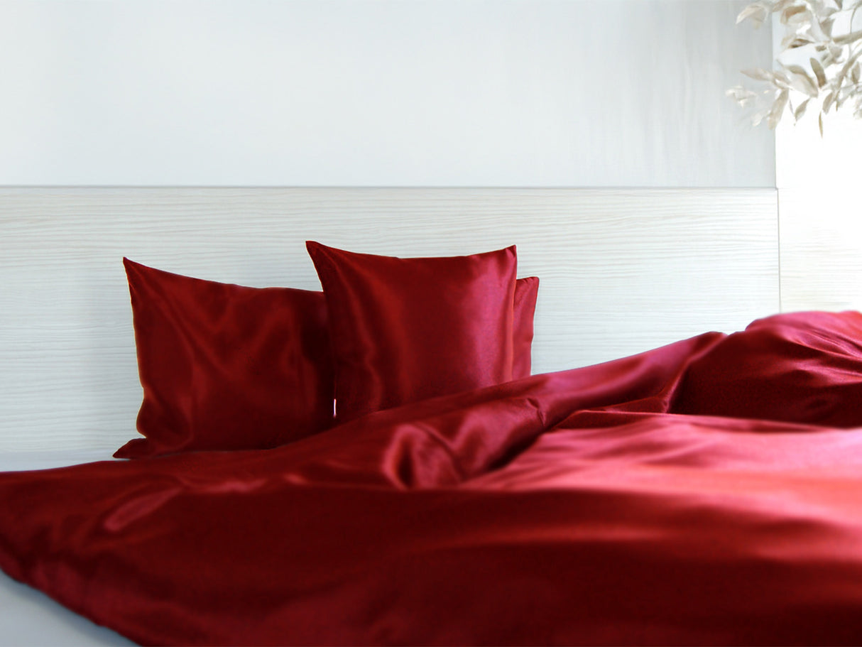 Karmin-rote Glanz Satin Bettwaesche in einem hellen Bett.