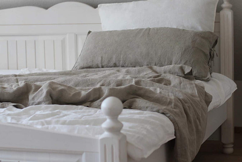 weiße und beige farbige 100% Leinen Bettwäsche einladend drapiert in einem Bett