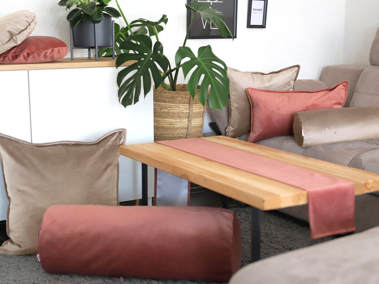 Altrosane und taupe-farbene Samt Kissenbezuege und ein altrosa Samt Tischband sind in einem Wohnzimmer dekoriert.