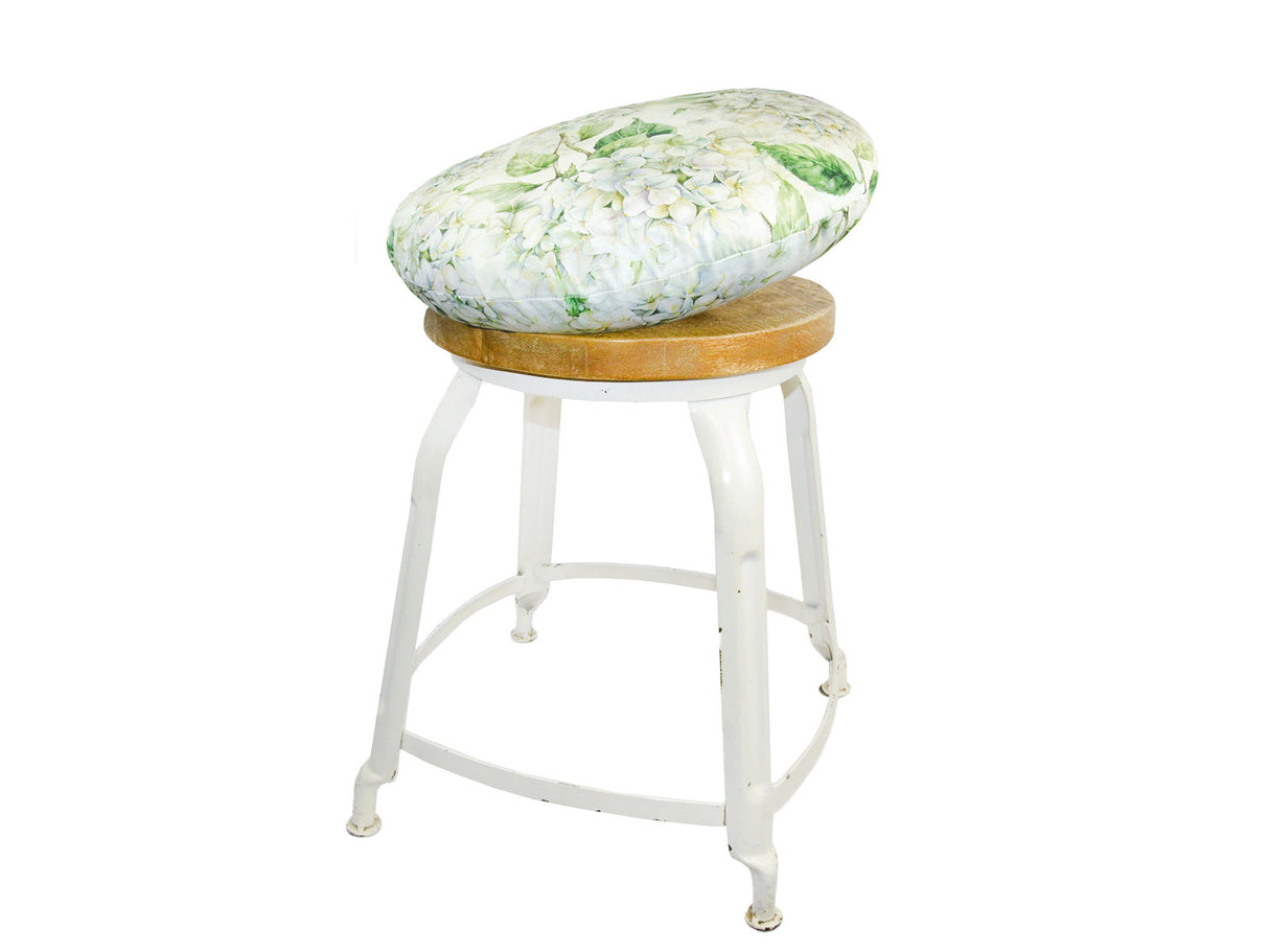 Auf einem Hocker liegt ein runder Kissenbezug im Landhausstil, bedruckt mit weissen Hortensien-Blueten.