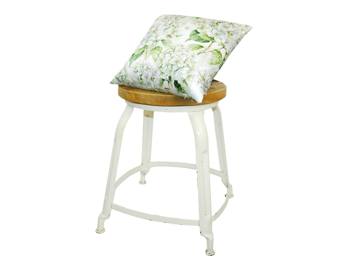 Auf einem Hocker liegt ein quadratischer Kissenbezug im Landhausstil, bedruckt mit weissen Hortensien-Blueten.