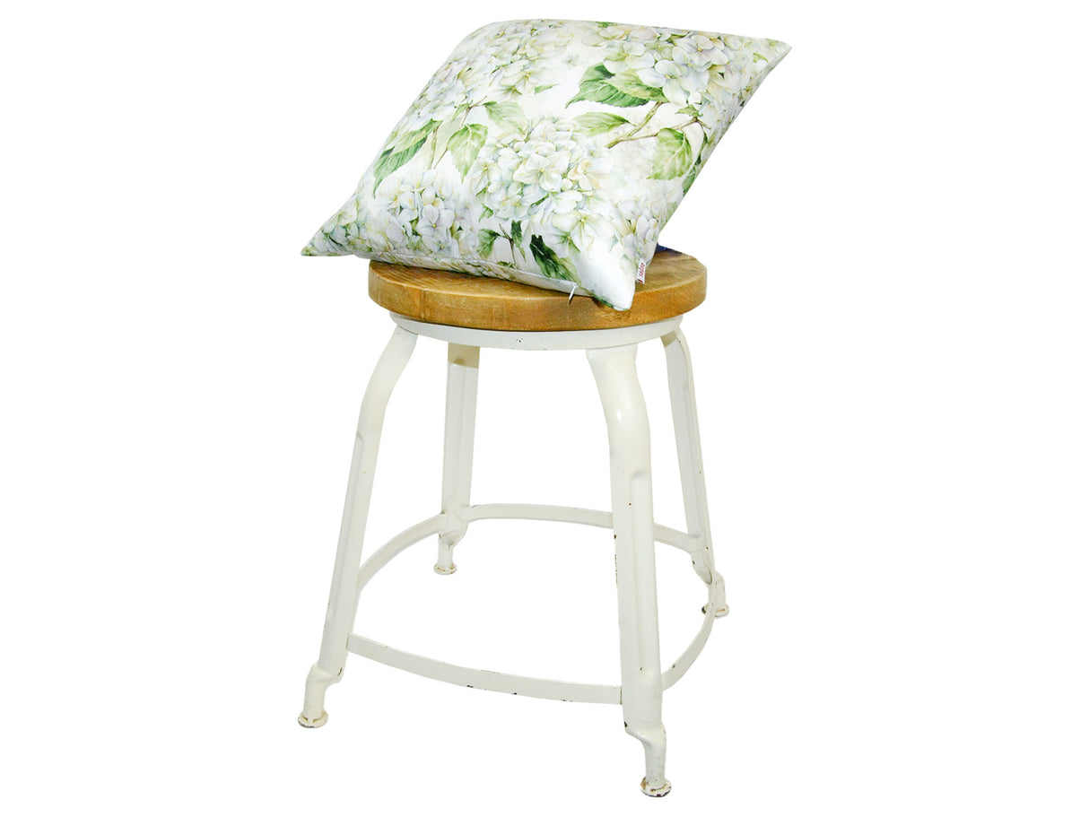 Auf einem Hocker liegt ein quadratischer Kissenbezug im Landhausstil, bedruckt mit weissen Hortensien-Blueten.