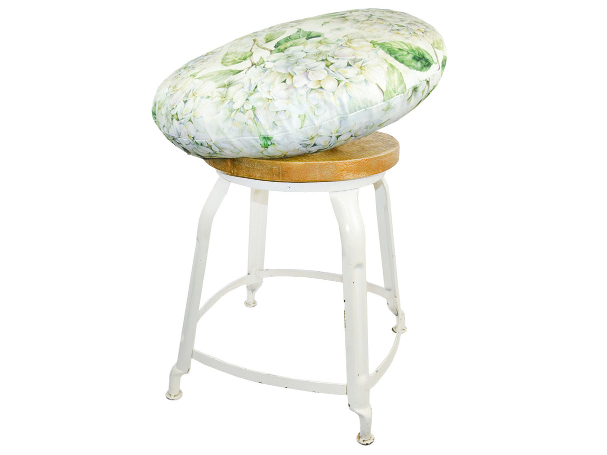 Auf einem Hocker liegt ein runder Kissenbezug im Landhausstil, bedruckt mit weissen Hortensien-Blueten.