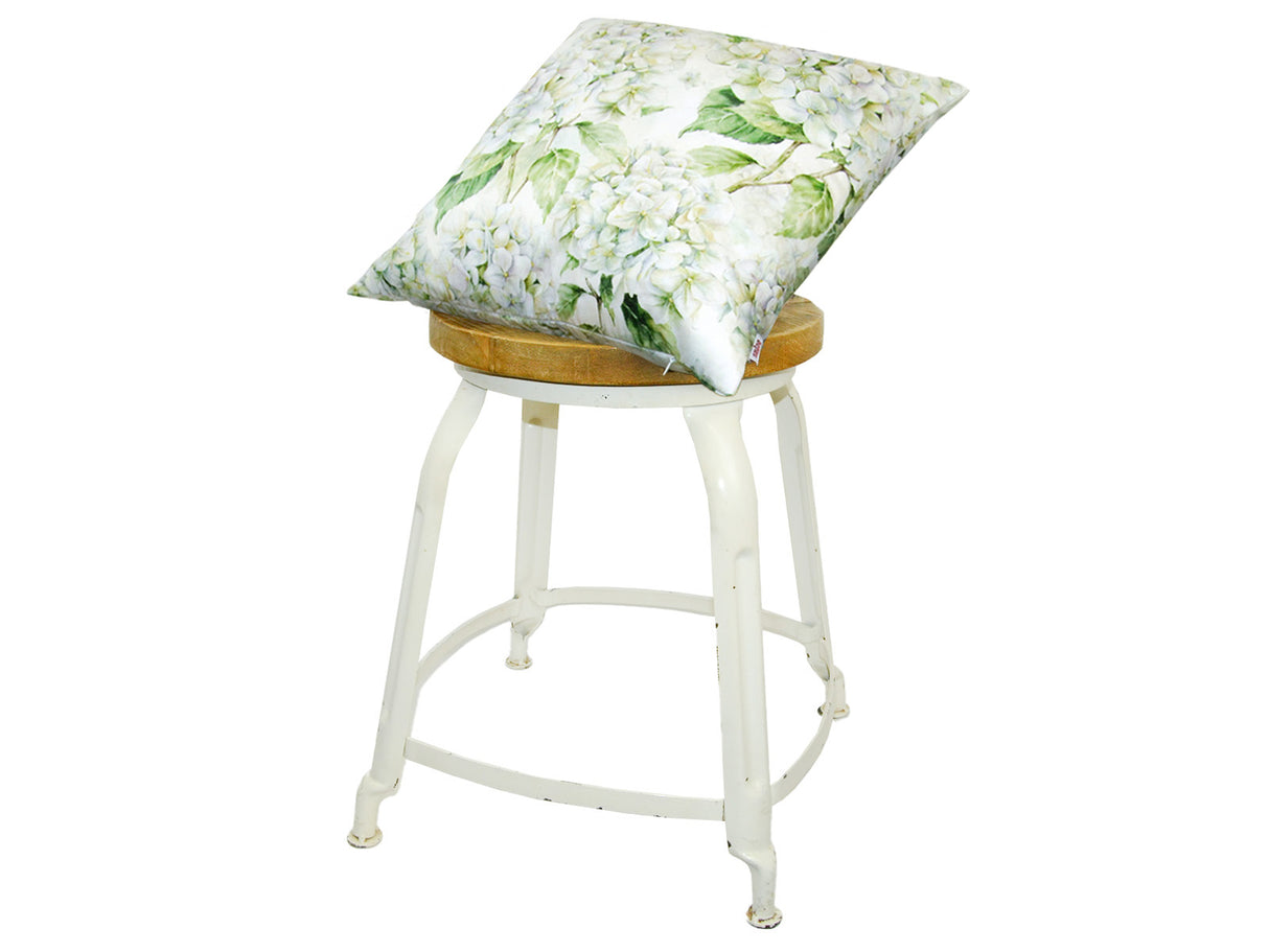 Auf einem Hocker liegt ein quadratischer Kissenbezug im Landhausstil, bedruckt mit weissen Hortensien-Blueten.