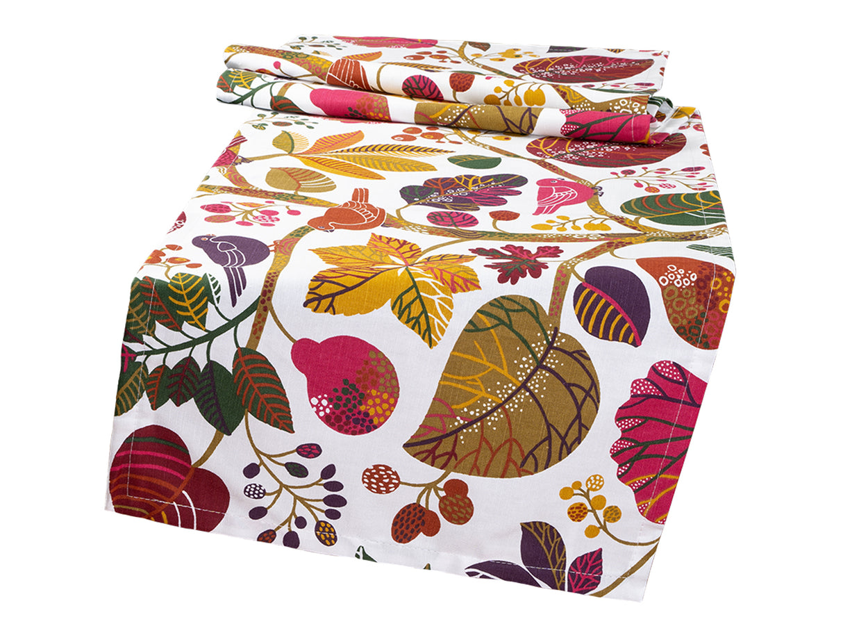 Ein Tischlaeufer bedruckt mit bunten Blaettern, Zweigen und Voegeln auf weissem Hintergrund.