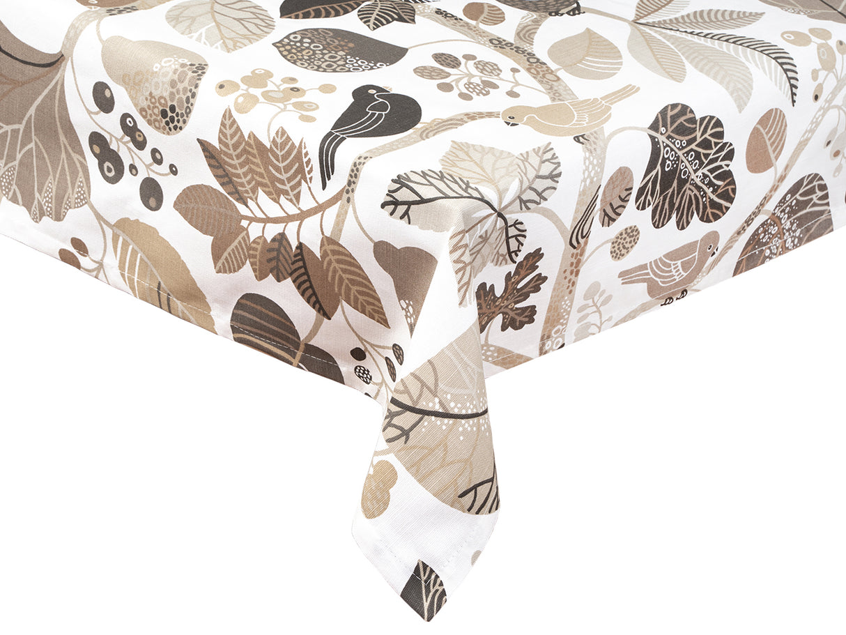 Eine Ecke einer Tischdecke bedruckt mit taupefarbenen und braunen Blaettern, Zweigen und Voegeln auf weissem Hintergrund.