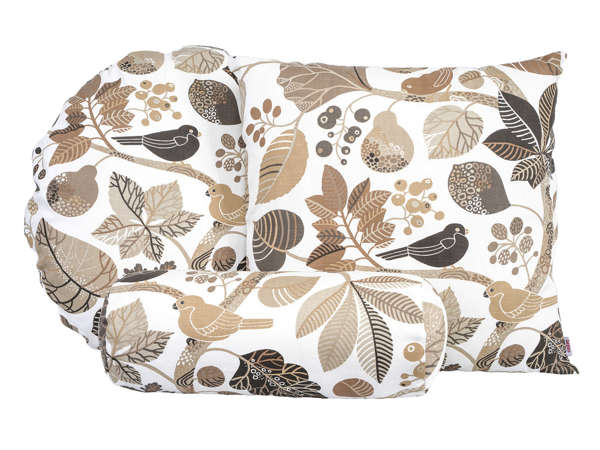 Ein runder und ein quadratischer Kissenbezug und ein Nackenrollenbezug mit braunen und taupefarbenen Blaettern und Zweigen auf weissem Hintergrund.