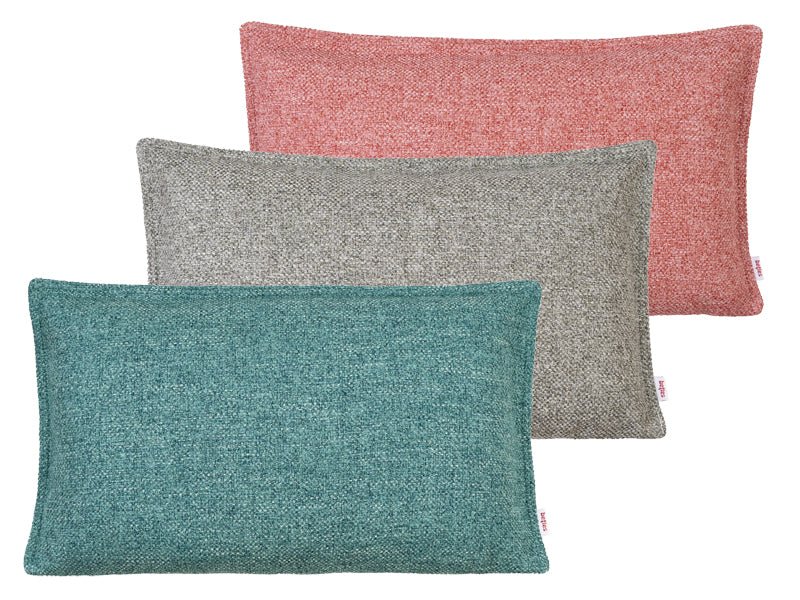 Drei rechteckige Kissen bezogen mit einer Boucle-Kissenhuelle in den Farben petrol, hellgrau und rot.