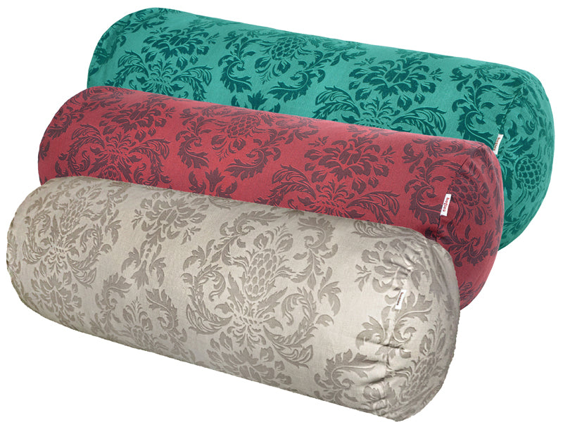 Drei Kissenrollen hintereinander, bezogen mit Kissenbezuegen in den Farben Beige, Rot und Petrol. Bedruckt sind die Bezuege mit barocken Ornamenten in der jeweiligen Farbe, nur etwas dunkler.