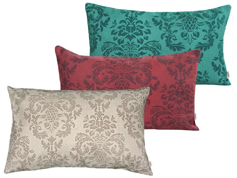 Drei rechteckige Kissen hintereinander, bezogen mit Kissenbezuegen in den Farben Beige, Rot und Petrol. Bedruckt sind die Bezuege mit barocken Ornamenten in der jeweiligen Farbe, nur etwas dunkler.