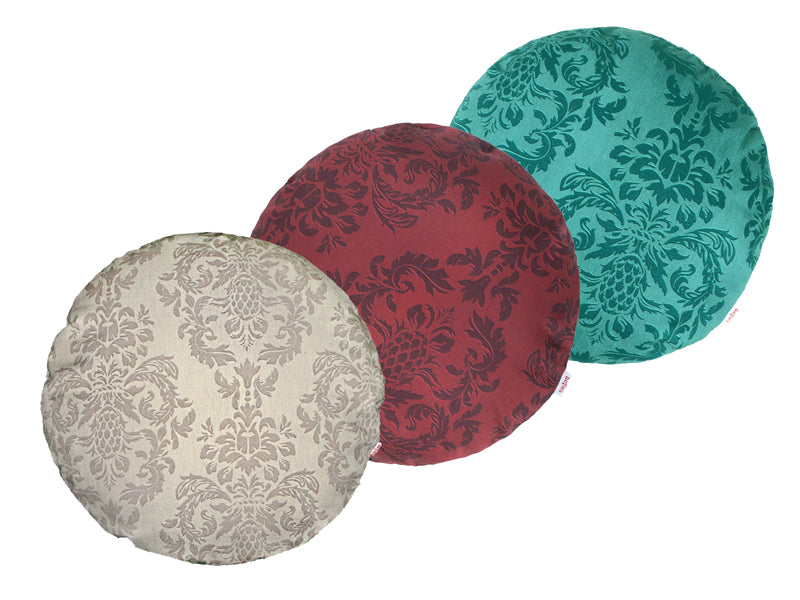 Drei runde Kissen hintereinander, bezogen mit Kissenbezuegen in den Farben Beige, Rot und Petrol. Bedruckt sind die Bezuege mit barocken Ornamenten in der jeweiligen Farbe, nur etwas dunkler.