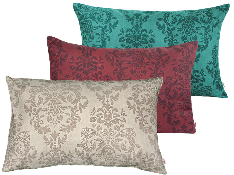 Drei rechteckige Kissen hintereinander, bezogen mit Kissenbezuegen in den Farben Beige, Rot und Petrol. Bedruckt sind die Bezuege mit barocken Ornamenten in der jeweiligen Farbe, nur etwas dunkler.
