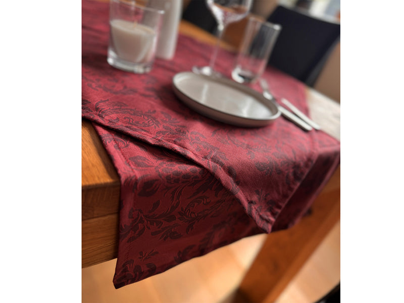 Roter Tischlaeufer, bedruckt mit barocken Ornamenten in einem dunkleren Rot.
