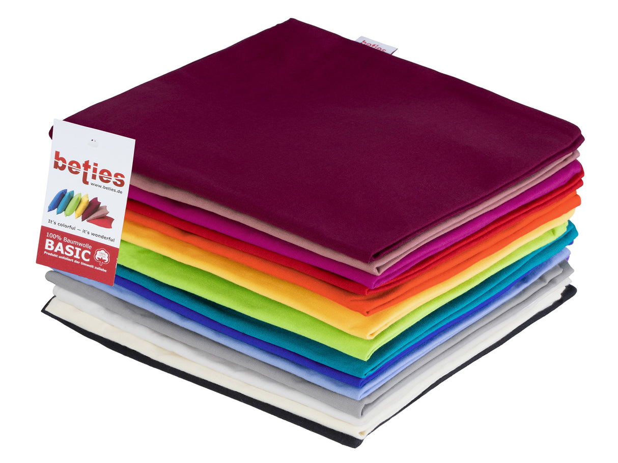 Ein Stapel gefalteter Kissenhuellen in kraeftigen Uni-Farben Schwarz, Hellbeige, Weiss, Hellgrau, Hellblau, Royal-Blau, Petrol, Apfelgruen, Gelb, Orange, Rot, Pink, Altrosa und Weinrot. 