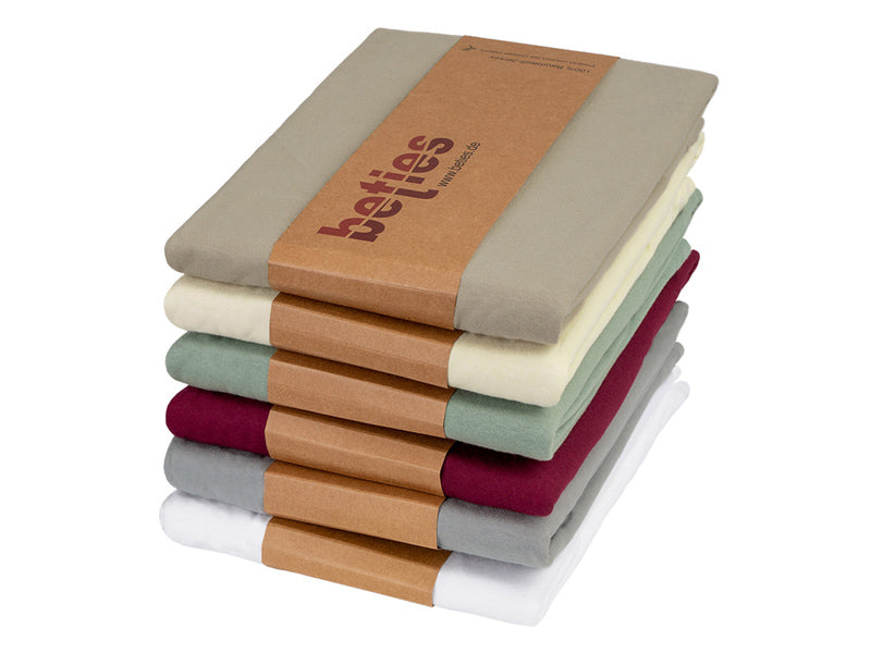 Stapel mit gefalteten Kissenbezuegen in den Uni-Farben Weiss, Hellgrau, Weinrot, Gruen, Natur und Beige.