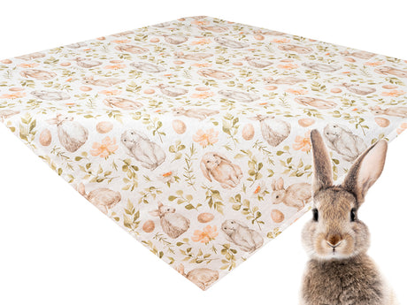Weisse Mitteltischdecke flach liegend bedruckt mit braunen Haeschen, weissen und orangen Blumen und gruenen Zweigen. Davor sitzt ein lebensechter Hase im Bild.