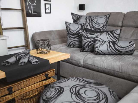 modernes Industrie style Wohnzimmer mit vielen beties Mystik Kissen auf den Sofa liegend  Kissenhbezüge in grau mit schwarzen Kreisen