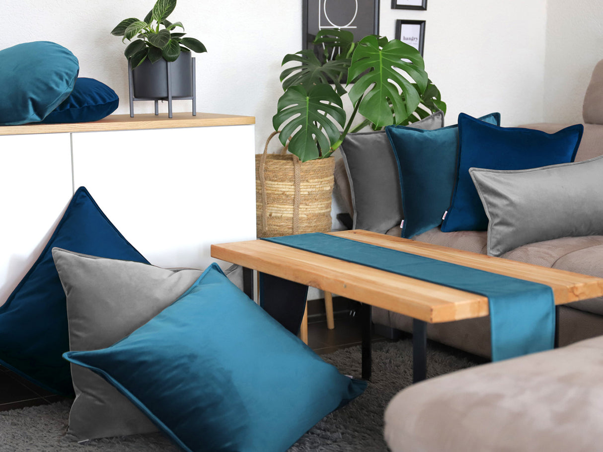 Admiral-blaue, graue und petrol-farbene Samt Kissenbezuege und ein petrol-farbenes Samt Tischband sind in einem Wohnzimmer dekoriert.