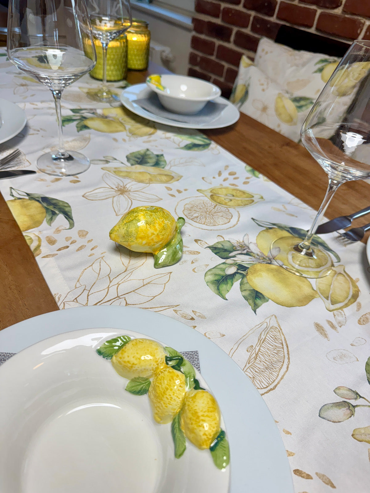 Hellbeiger Tischläufer mit Zitronenmuster und goldenen Akzenten, der flach auf einem Tisch liegt.