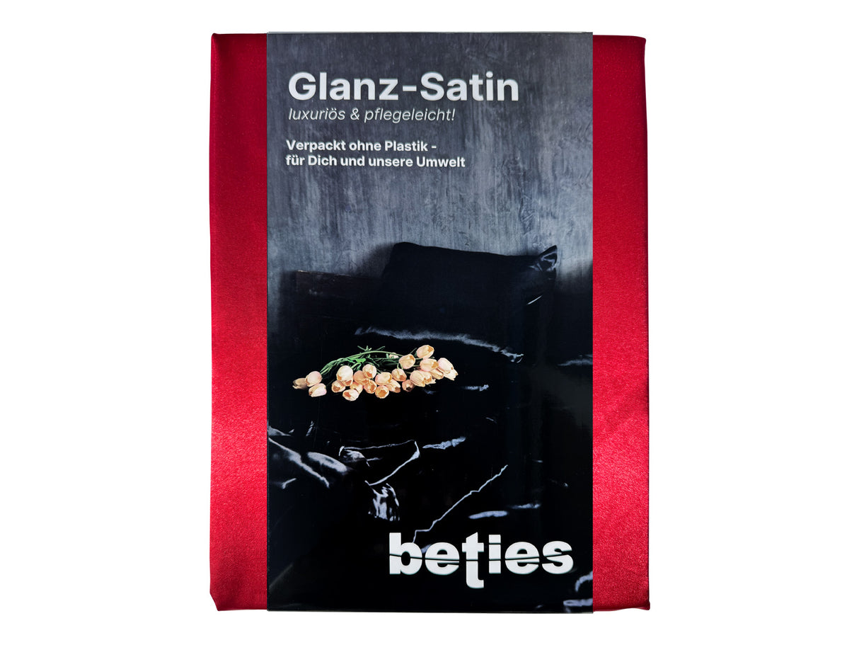 Karmin-rotes Glanz Satin Spannbetttuch. Verpackt mit einer edlen, schwarzen Karton-Banderole.