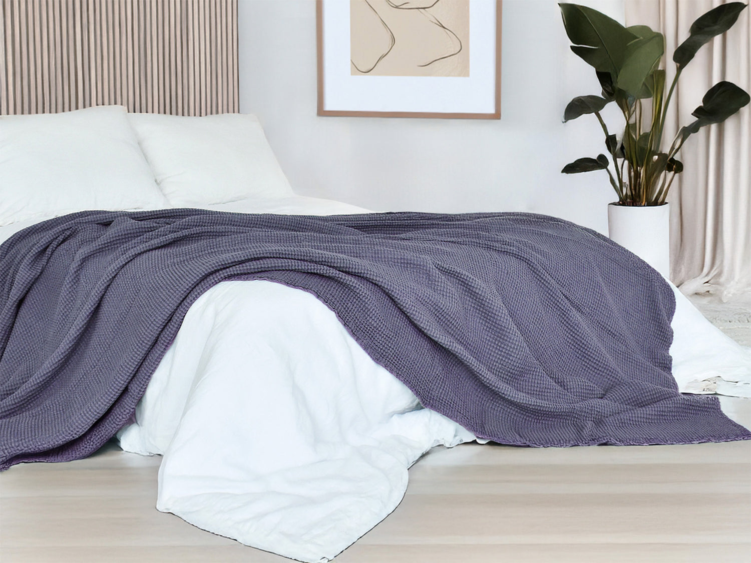 In einem Schlafzimmer liegt eine Fjord-blaue Tagesdecke aus der beties "PUR.NATURE" Serie auf einem Bett ausgebreitet.