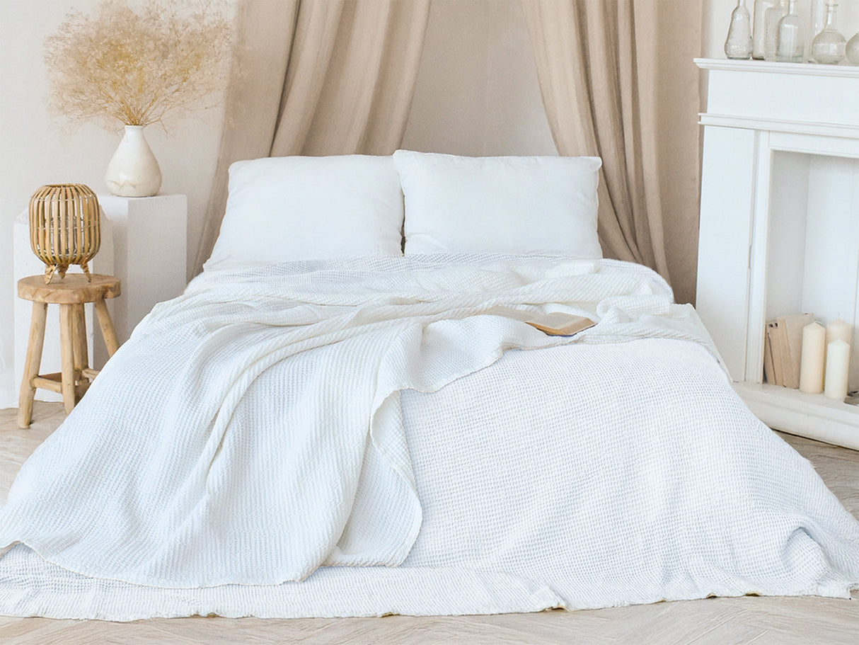 In einem Schlafzimmer liegen zwei Gletscher-weisse Tagesdecken aus der beties "PUR.NATURE" Serie auf einem Bett ausgebreitet.