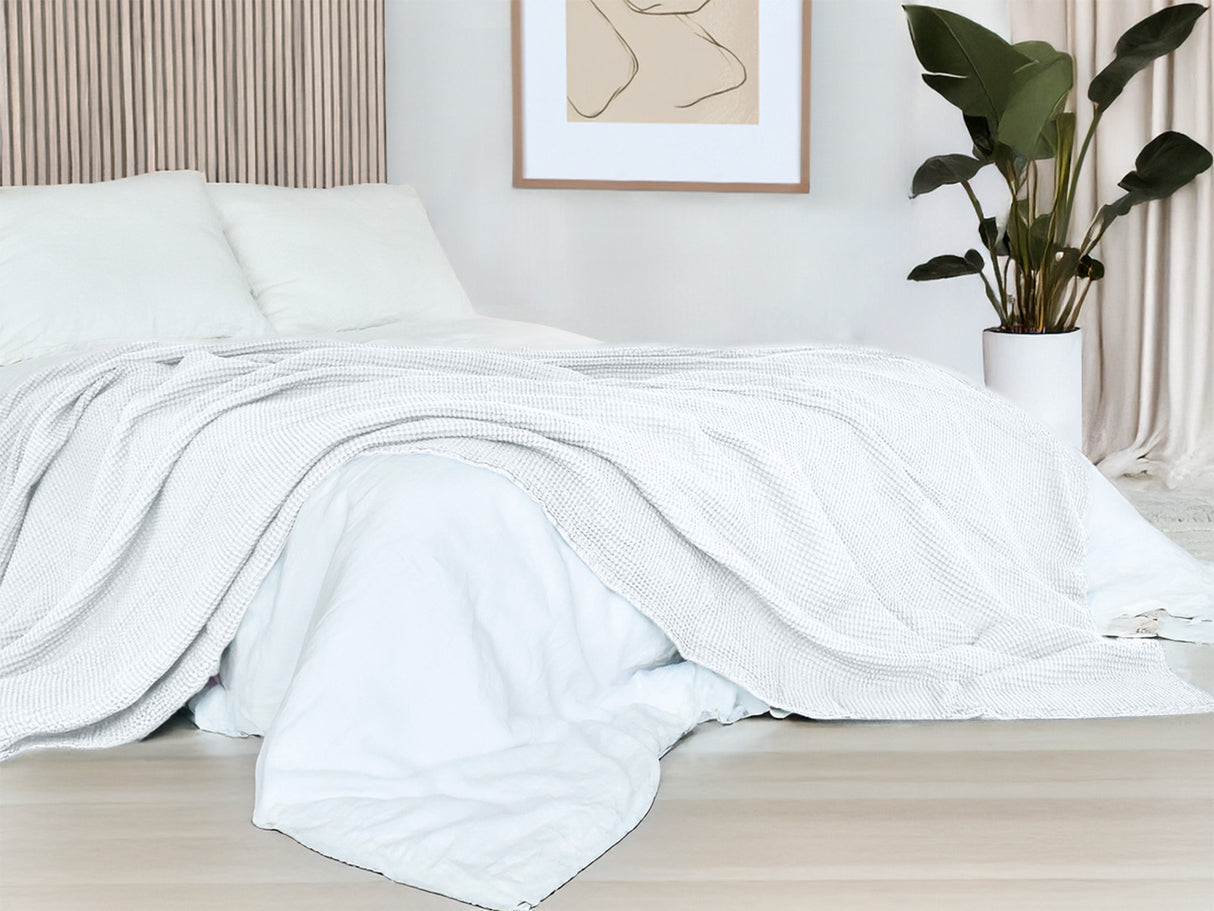 In einem Schlafzimmer liegt eine Gletscher-weisse Tagesdecke aus der beties "PUR.NATURE" Serie auf einem Bett ausgebreitet.