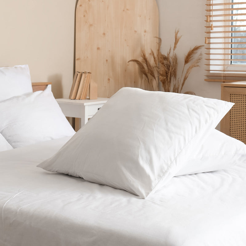 Weiß bezogenes Bett mit weißen Kissen in einem modernen Schlafzimmer.